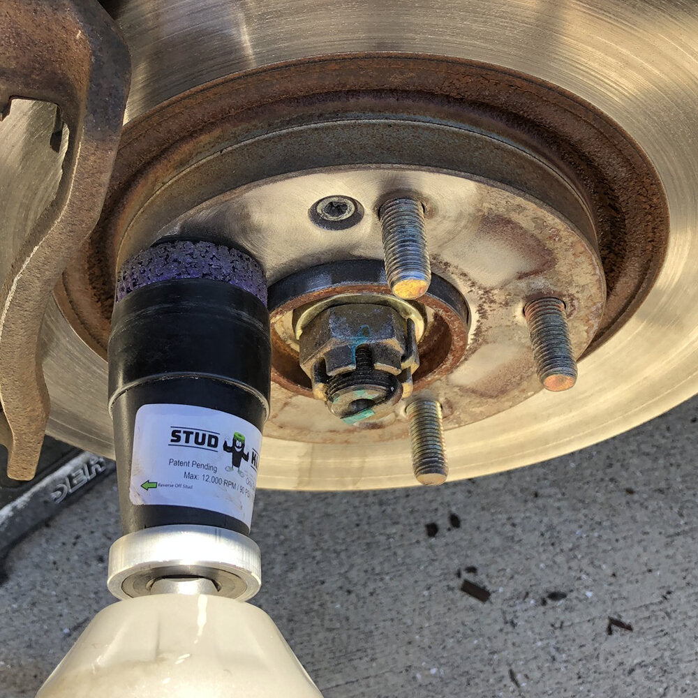 Stud cleaning tool attached to impact wrench on wheel hub
